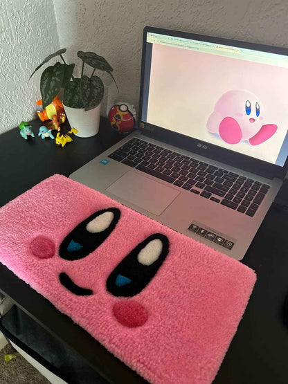 Pink plush character rug with Kirby-style face, blue eye accents and black outline