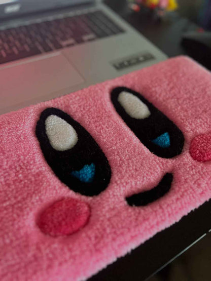 Pink plush character rug section with Kirby-style eye shapes, blue pupils and red nose