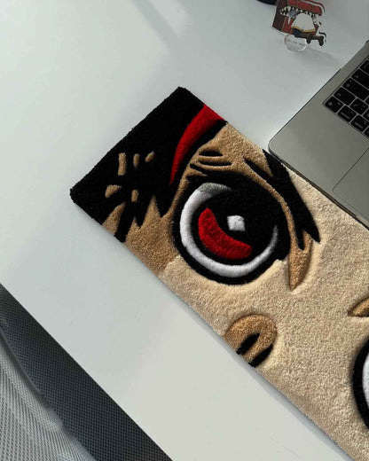 Handmade anime tufted desk mat corner with close-up red eye and black markings on tan
