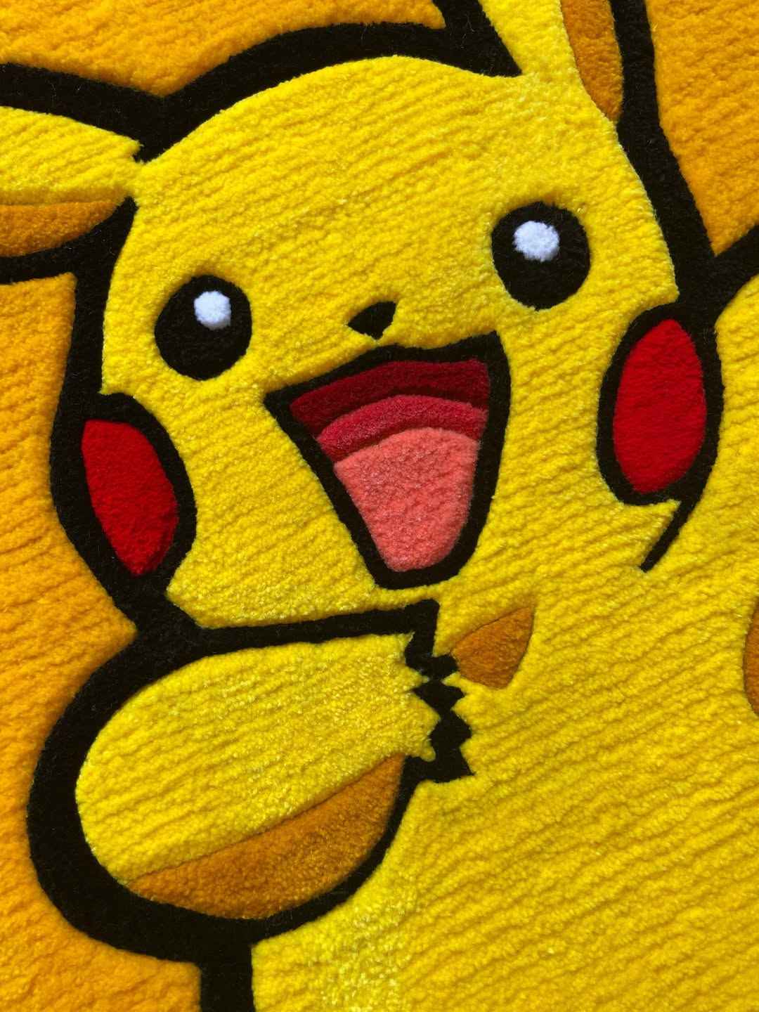 Pikachu rug close-up with big eyes, open mouth, and red cheek accents