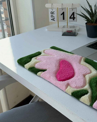 Handmade tufted floral desk mat with green edges and pink flower shapes